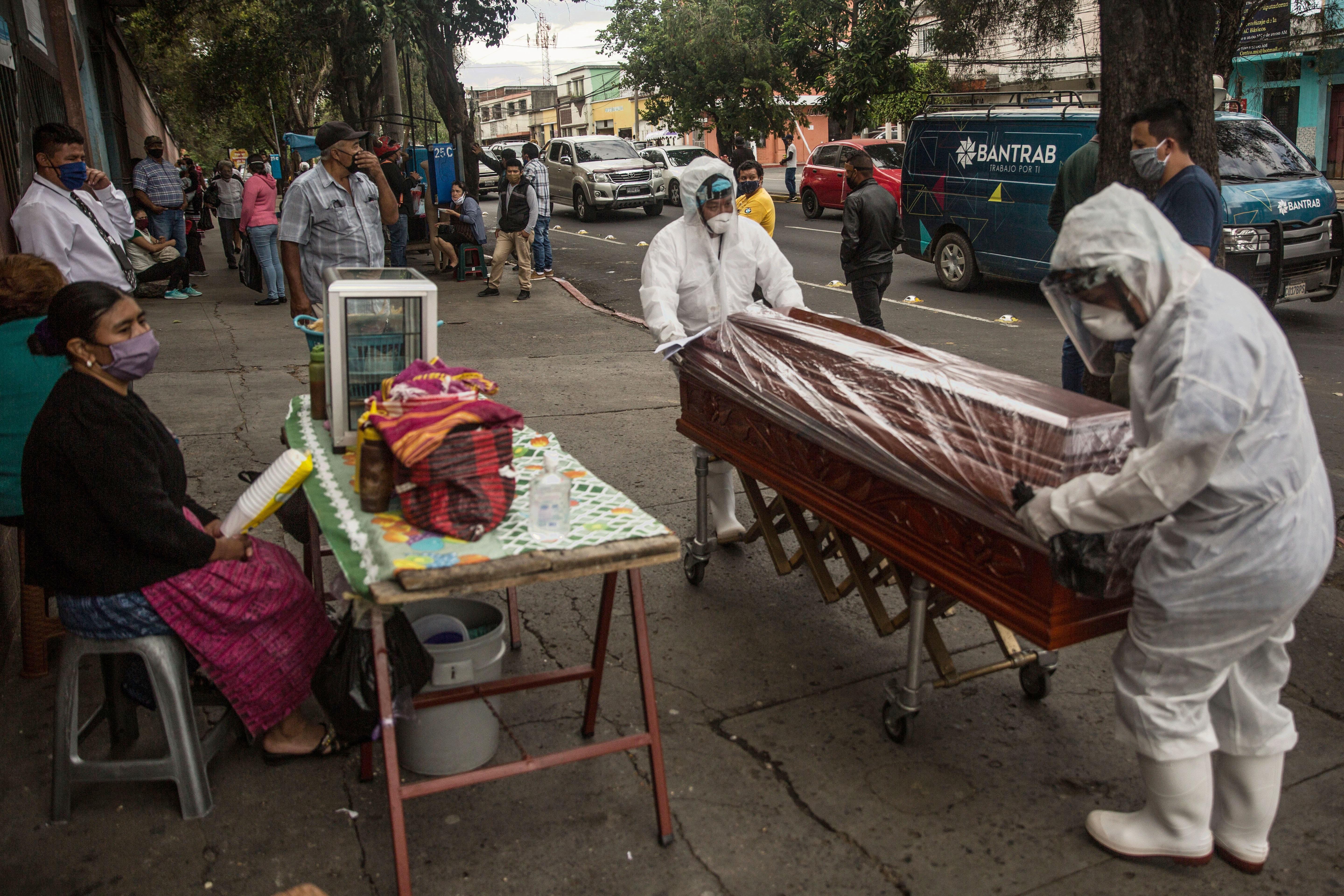 Empleados funerarios trasladan el féretro de una víctima de coronavirus, quien murió en la emergencia del Hospital Nacional San Juan de Dios el 28 de mayo de 2020. (Foto Prensa Libre: EFE)