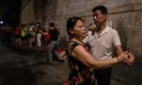 TOPSHOT - This photo taken on August 5, 2020 shows couples dancing next to the Yangtze River in Wuhan in Chinas central Hubei province. - The city's convalescence since a 76-day quarantine was lifted in April has brought life and gridlocked traffic back onto its streets, even as residents struggle to find their feet again. Long lines of customers now stretch outside breakfast stands, a far cry from the terrified crowds who queued at city hospitals in the first weeks after a city-wide lockdown was imposed in late January to curb the spread of the COVID-19 coronavirus. (Photo by Hector RETAMAL / AFP)