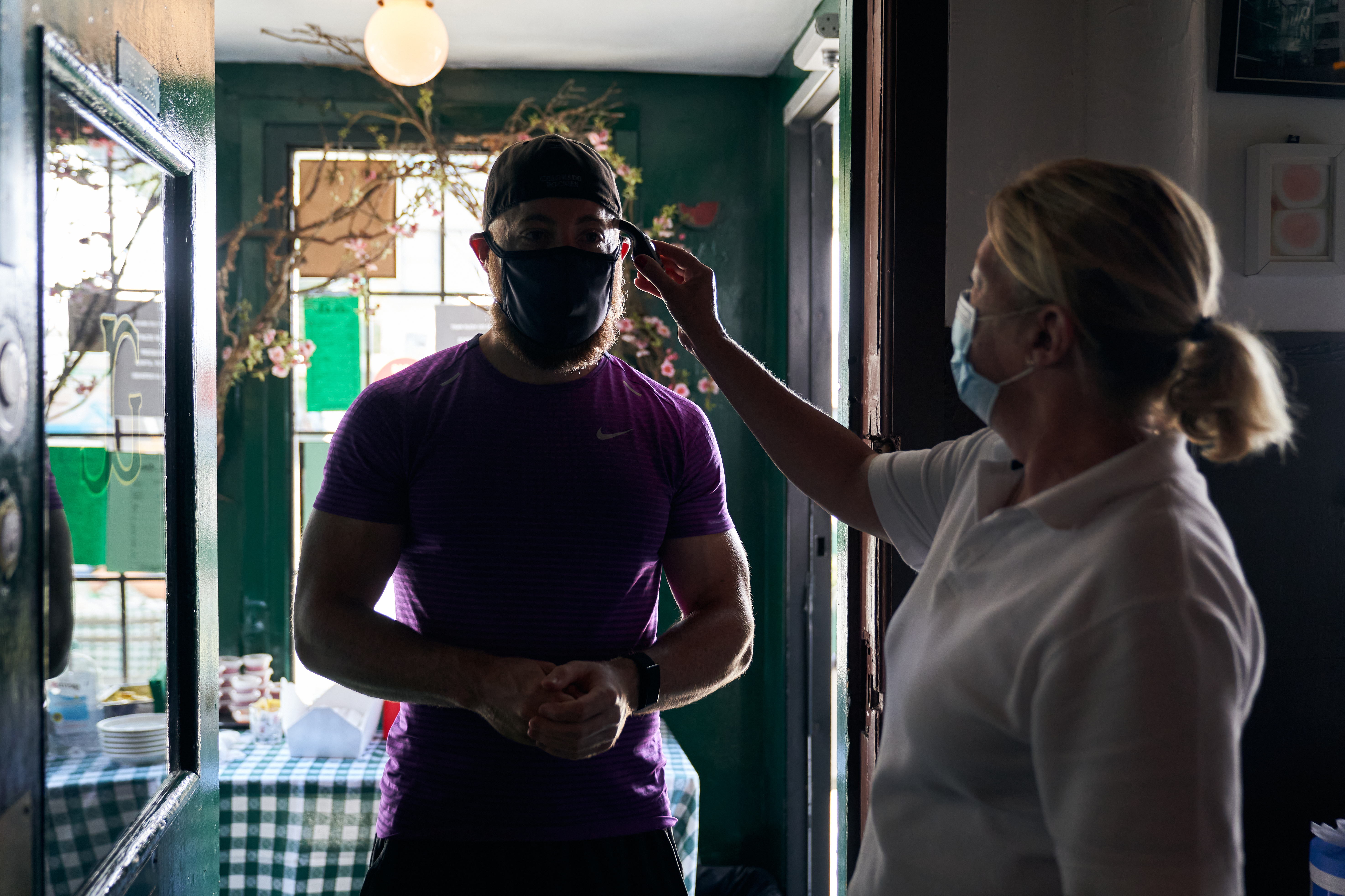 Un empleado le toma la temperatura a un cliente antes de que entre al baño en un J. G. Melon en la ciudad de Nueva York. Foto: Shravya Kag/The New York Times