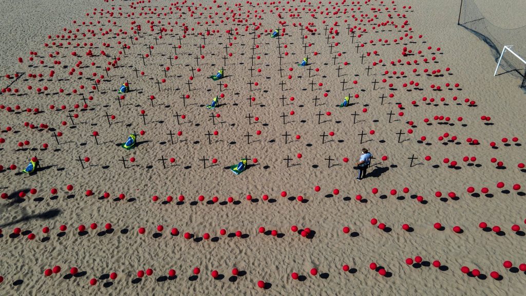 Con mil globos rojos en las arenas de la playa y cien de ellos fijados en cien cruces negras se rindió homenaje a los 100 mil brasileños fallecidos por la pandemia de coronavirus y se manifestaron en contra de la forma en que el Gobierno ha gestionado la crisis sanitaria. (Foto Prensa Libre: EFE)