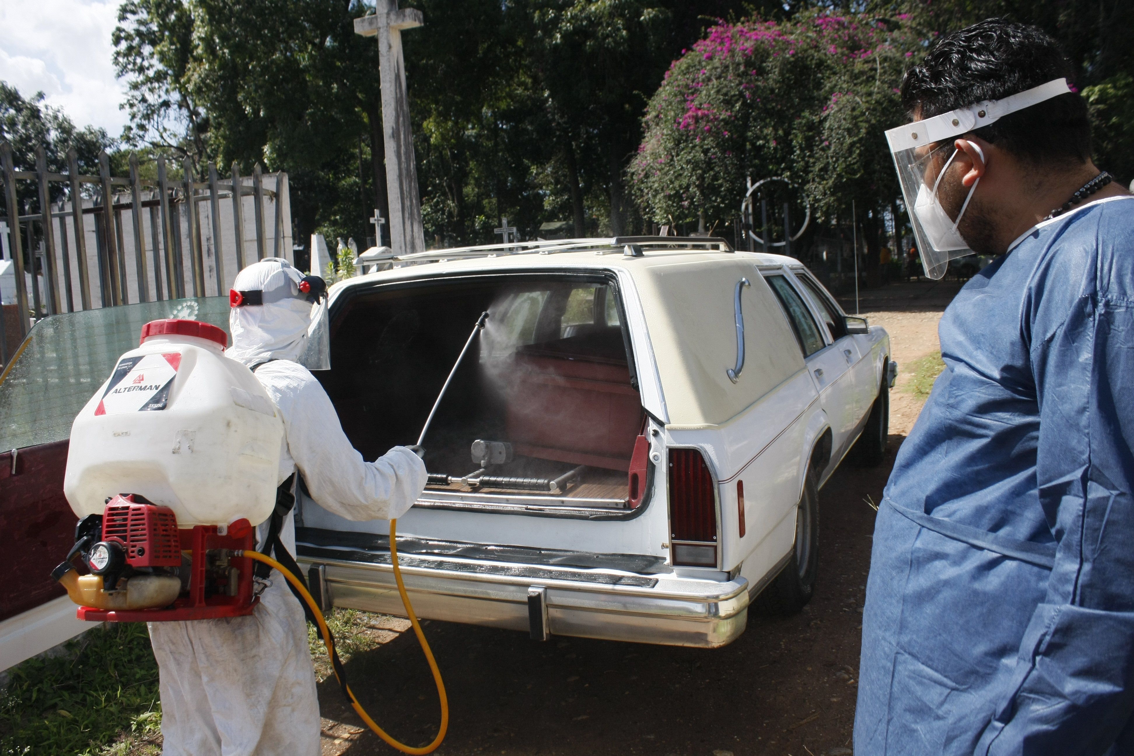 Un trabajador gubernamental desinfecta un ataúd con una víctima de covid-19 antes de bajarlo de un vehículo para proceder a enterrarlo hoy, en San Cristóbal (Venezuela). Venezuela registró este viernes diez muertes por la COVID-19 y 890 nuevas infecciones con lo que el total de contagios se ubica en 65.174, informó el Ministerio de Comunicación e Información. (Foto Prensa Libre: EFE)