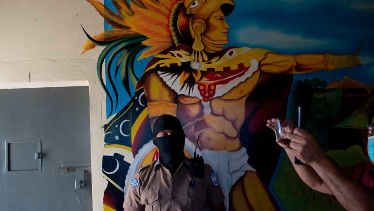 Un guardia penitenciario captado frente a un mural de la prisión de Quezaltepeque, El Salvador. (Foto Prensa Libre: AFP)