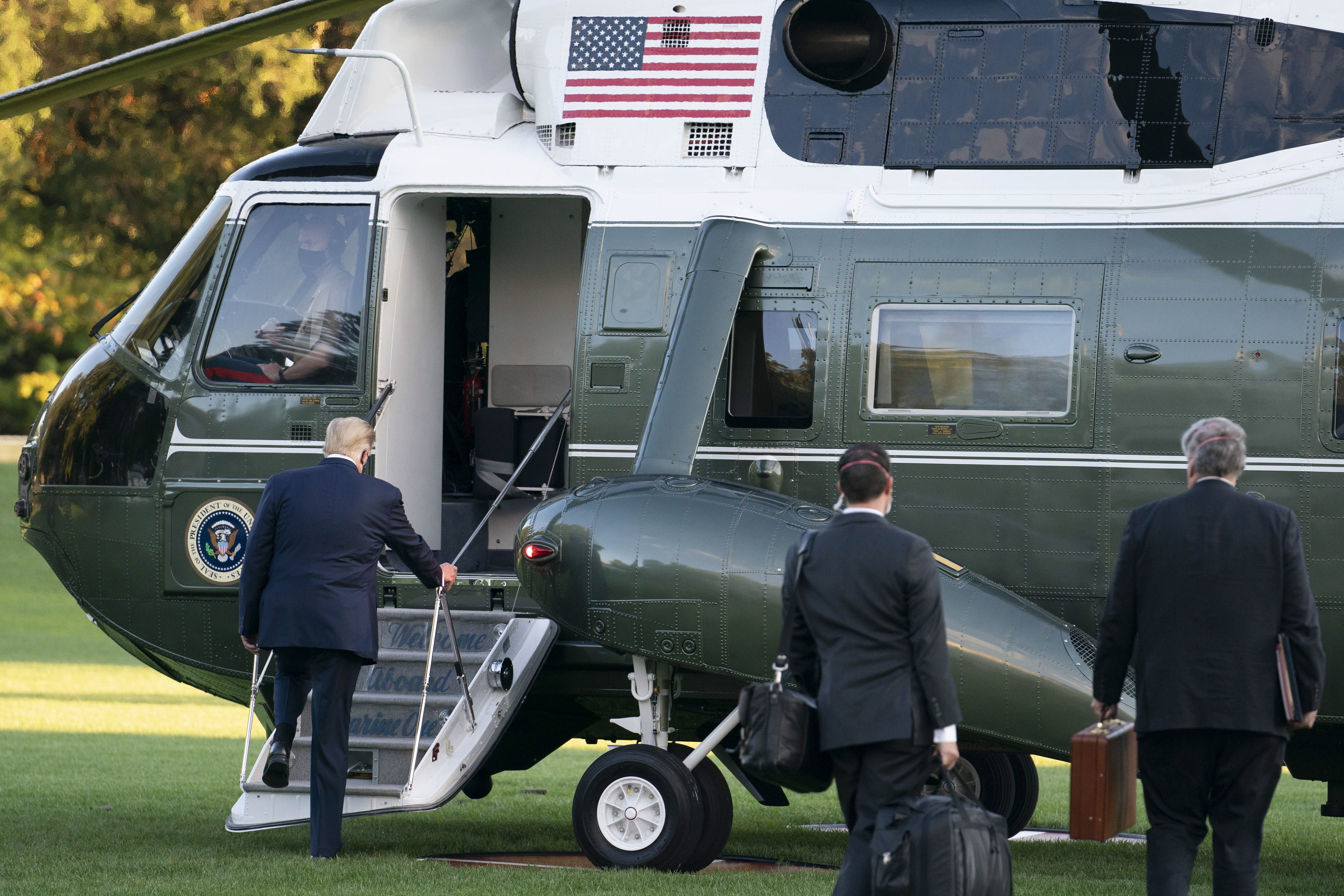 El presidente Donald Trump sale de Casa Blanca caminando con una mascarilla para subir a un helicóptero e ir al hospital. (Foto Prensa Libre: EFE)