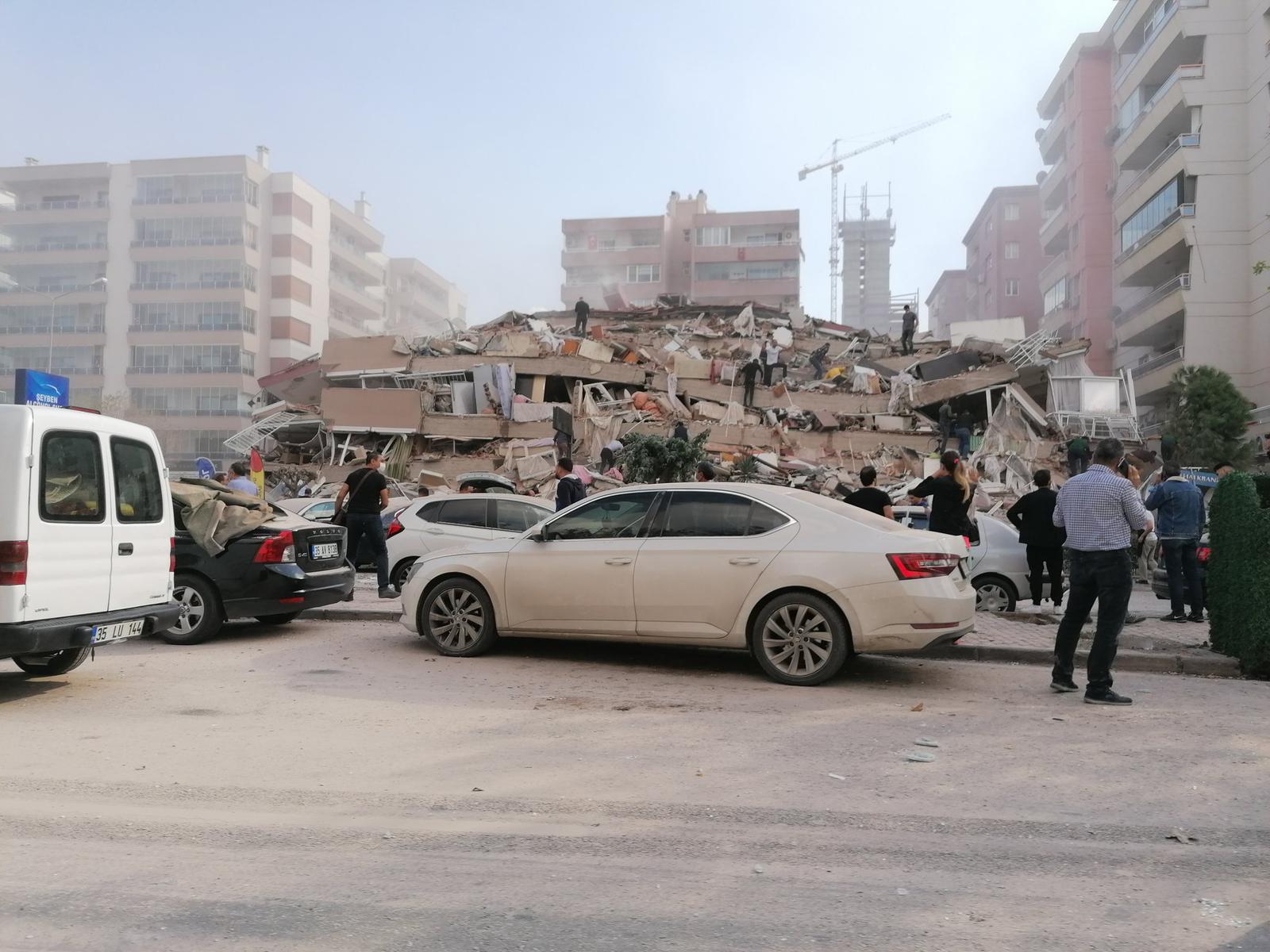 Personas observan una casa que colapsó en Izmir, Turquía por un temblor de 7.0 grados. (Foto Prensa Libre: AFP)