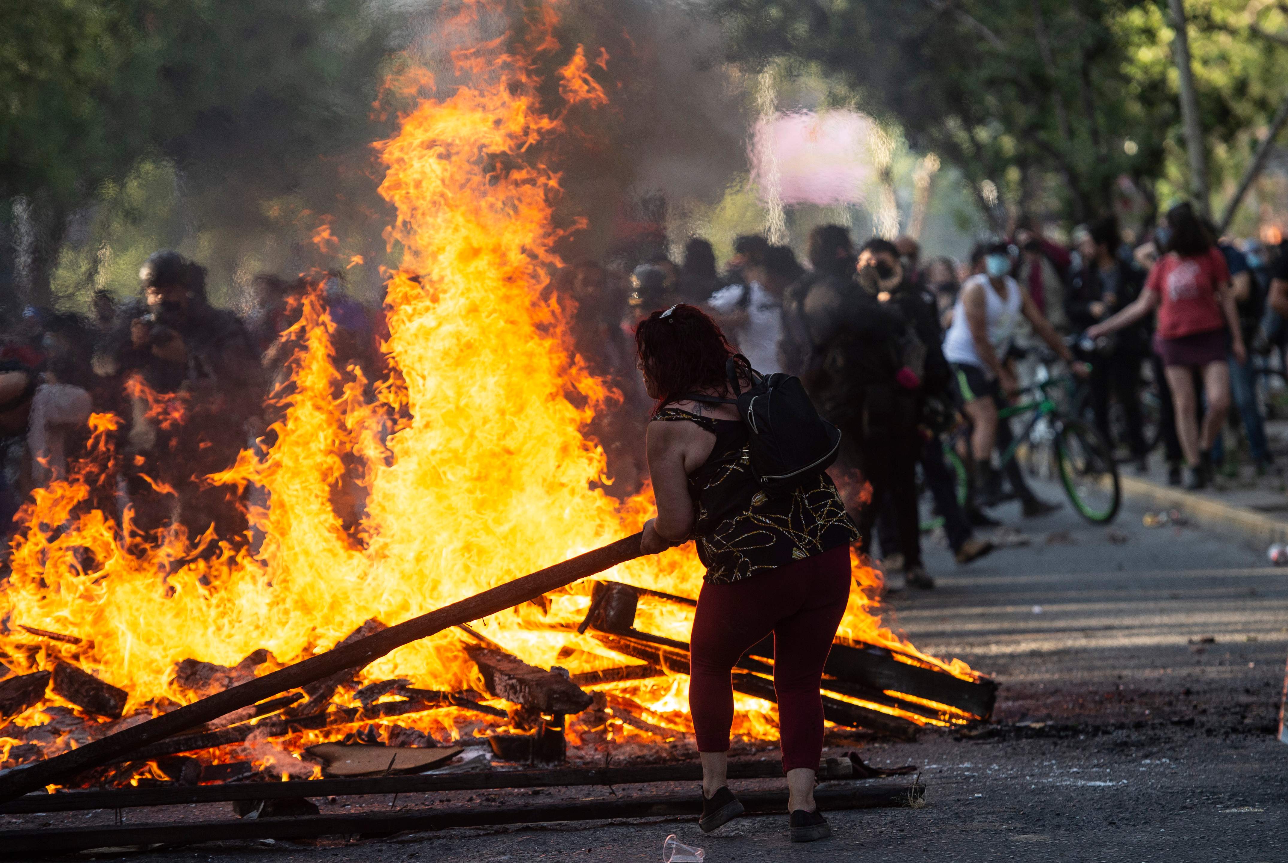 Un manifestante arroja una barda al fuego durante el choque de policías con la protesta, en Santiago de Chile. (Foto Prensa Libre: AFP)