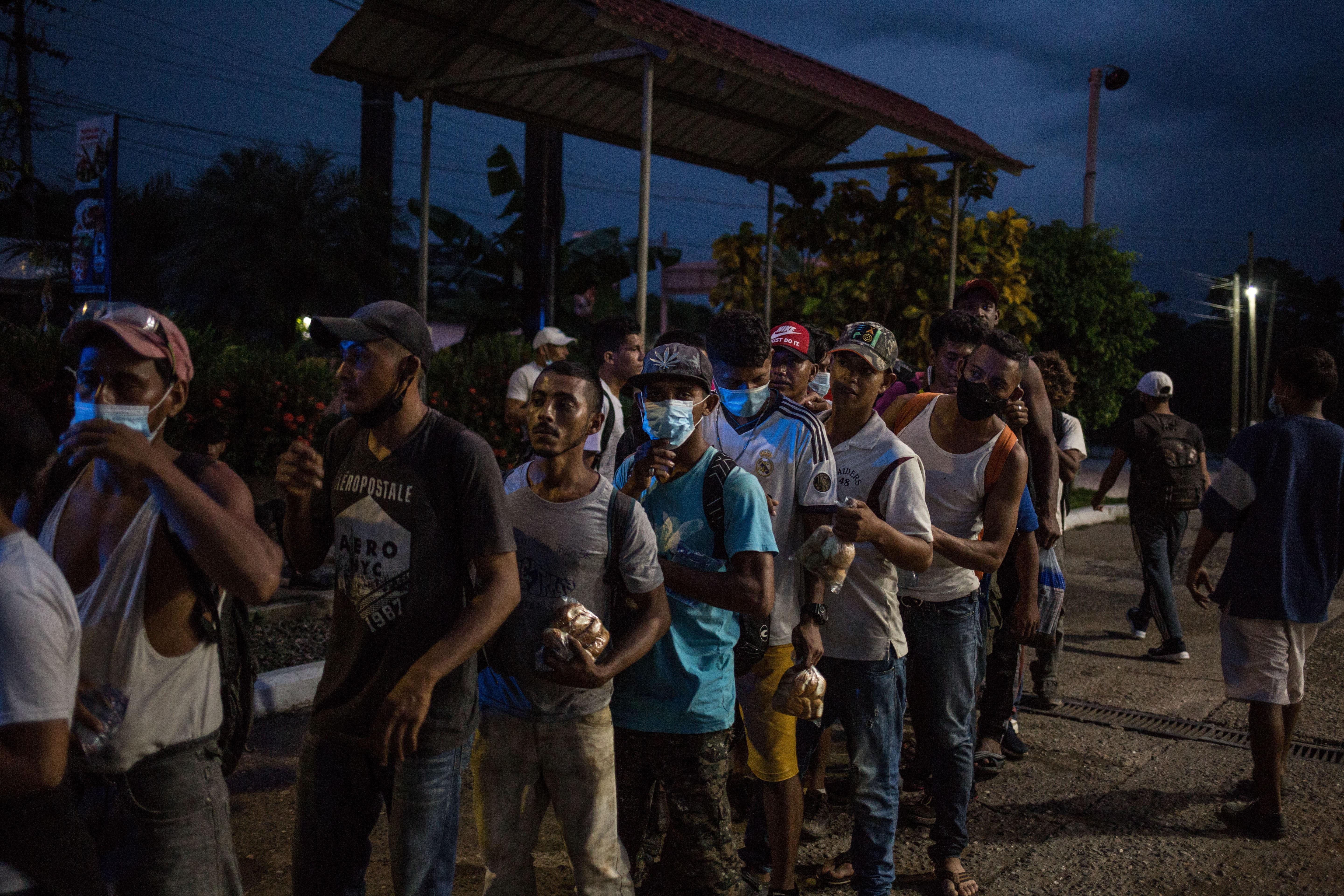 Migrantes hondureños esperan recibir alimentos de un grupo de voluntarios del albergue de migrantes de Esquipulas, Chiquimula. (Foto Prensa Libre: EFE)