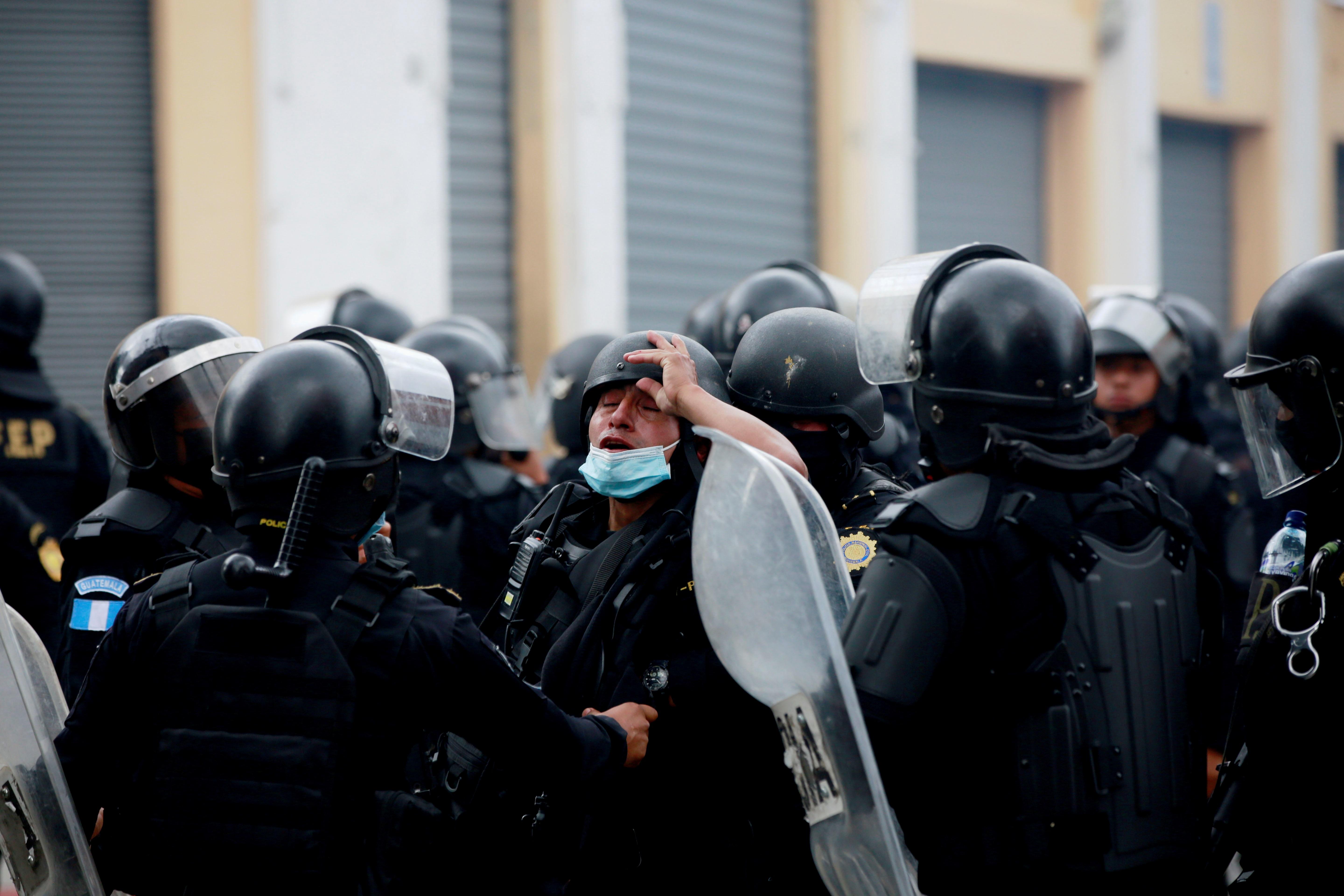 Un agente de la policía afectado por gases lacrimógenos es atendido durante las protestas en contra del Gobierno del presidente Alejandro Giammattei el pasado 21 de noviembre. (Foto Prensa Libre: EFE)