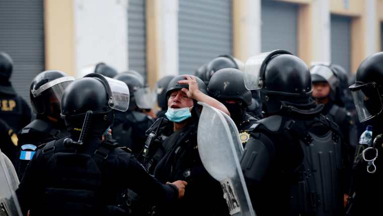 Un agente de la policía afectado por gases lacrimógenos es atendido durante las protestas en contra del Gobierno del presidente Alejandro Giammattei el pasado 21 de noviembre. (Foto Prensa Libre: EFE)