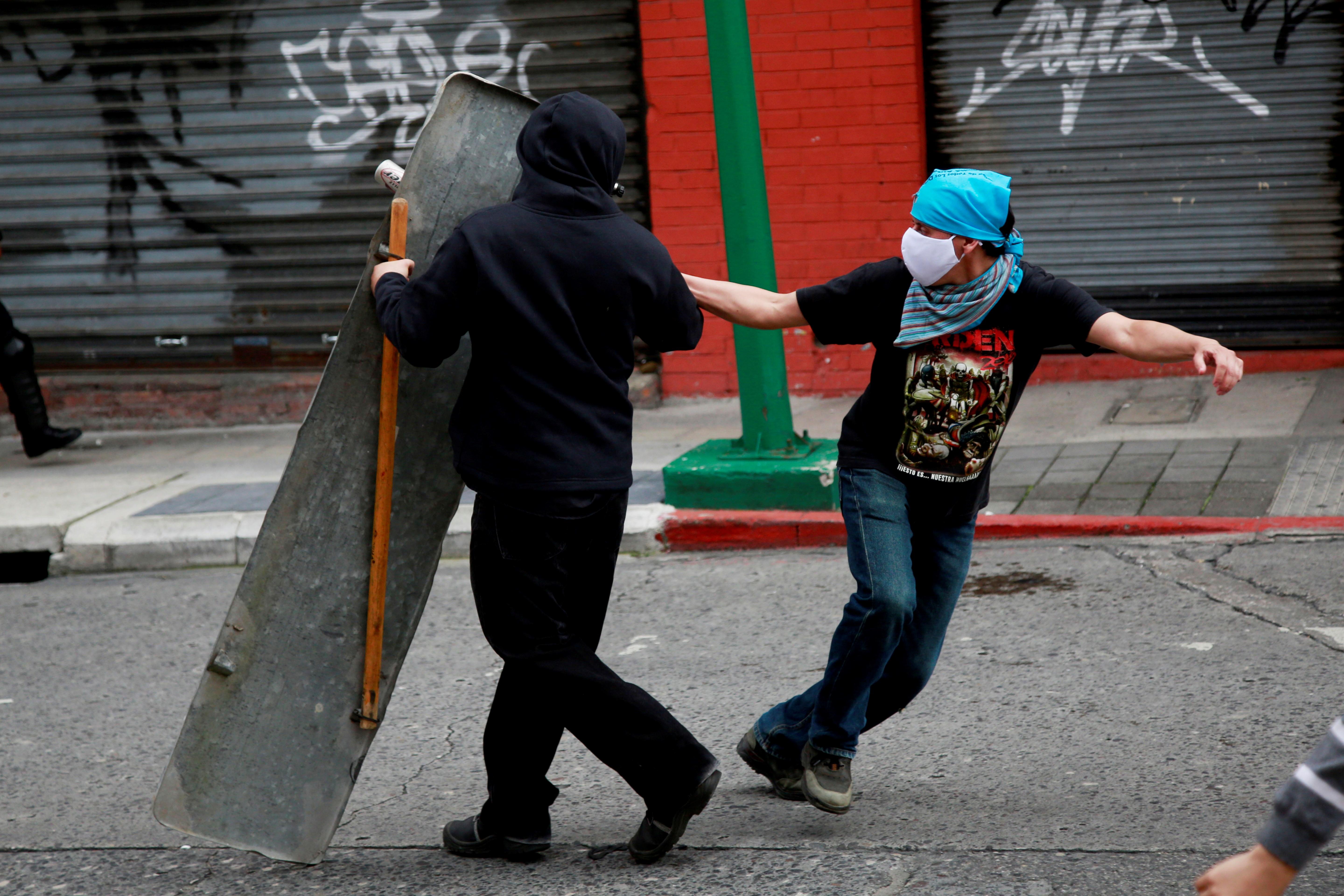 GRAF3316. CIUDAD DE GUATEMALA, 22/11/2020.- Los manifestantes arrojan piedras a la Policía durante los disturbios entre la policía y los manifestantes que ocuparon y prendieron fuego al Congreso en Ciudad de Guatemala este domingo tras las protestas en contra del Gobierno del presidente Alejandro Giammattei. Al menos 22 personas han sido detenidas durante los disturbios. EFE/ Esteban Biba