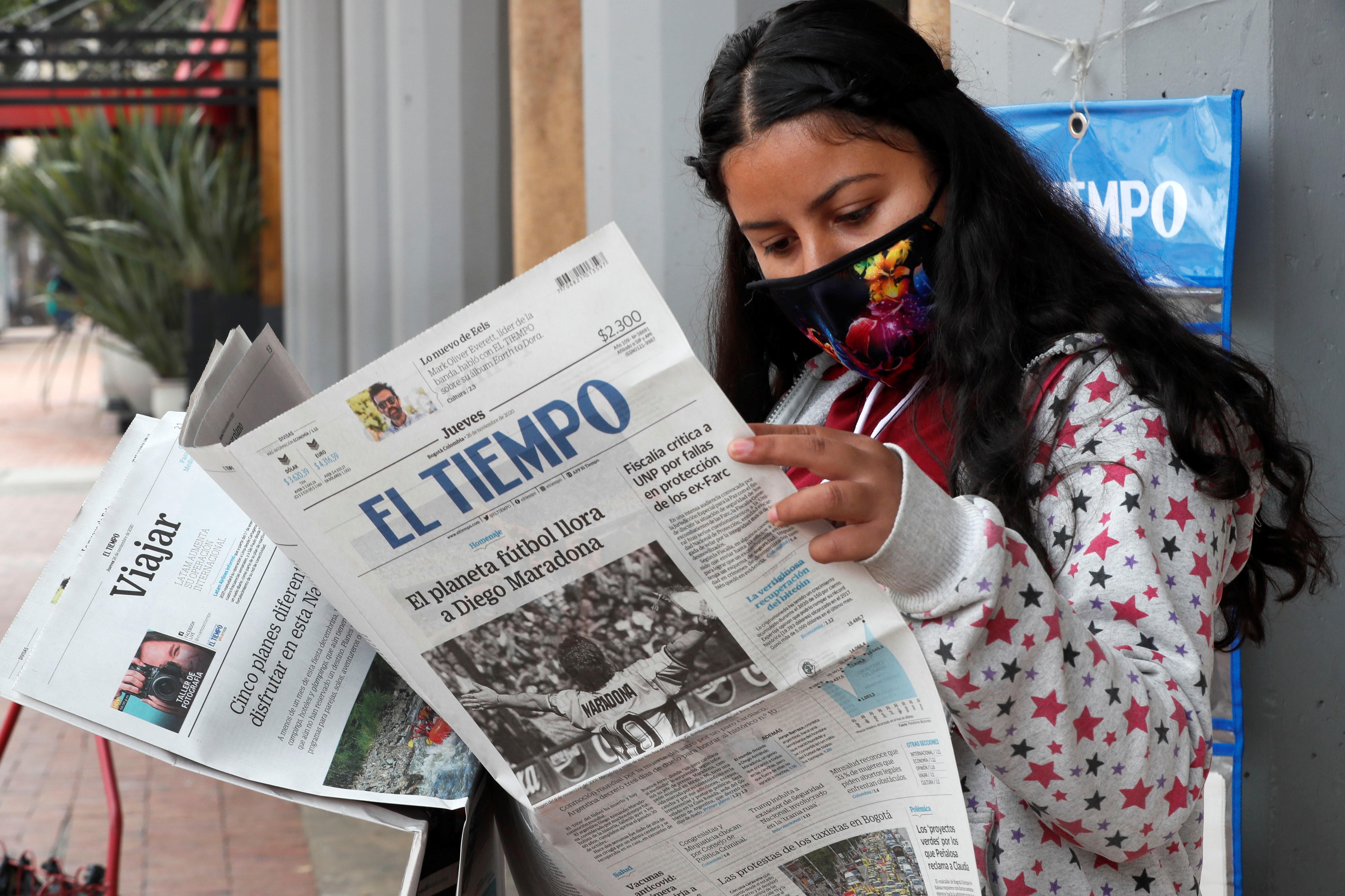 Una mujer lee el periódico El Tiempo, el cual registra en su portada el fallecimiento de Diego Armando Maradona. Foto Prensa Libre EFE.
