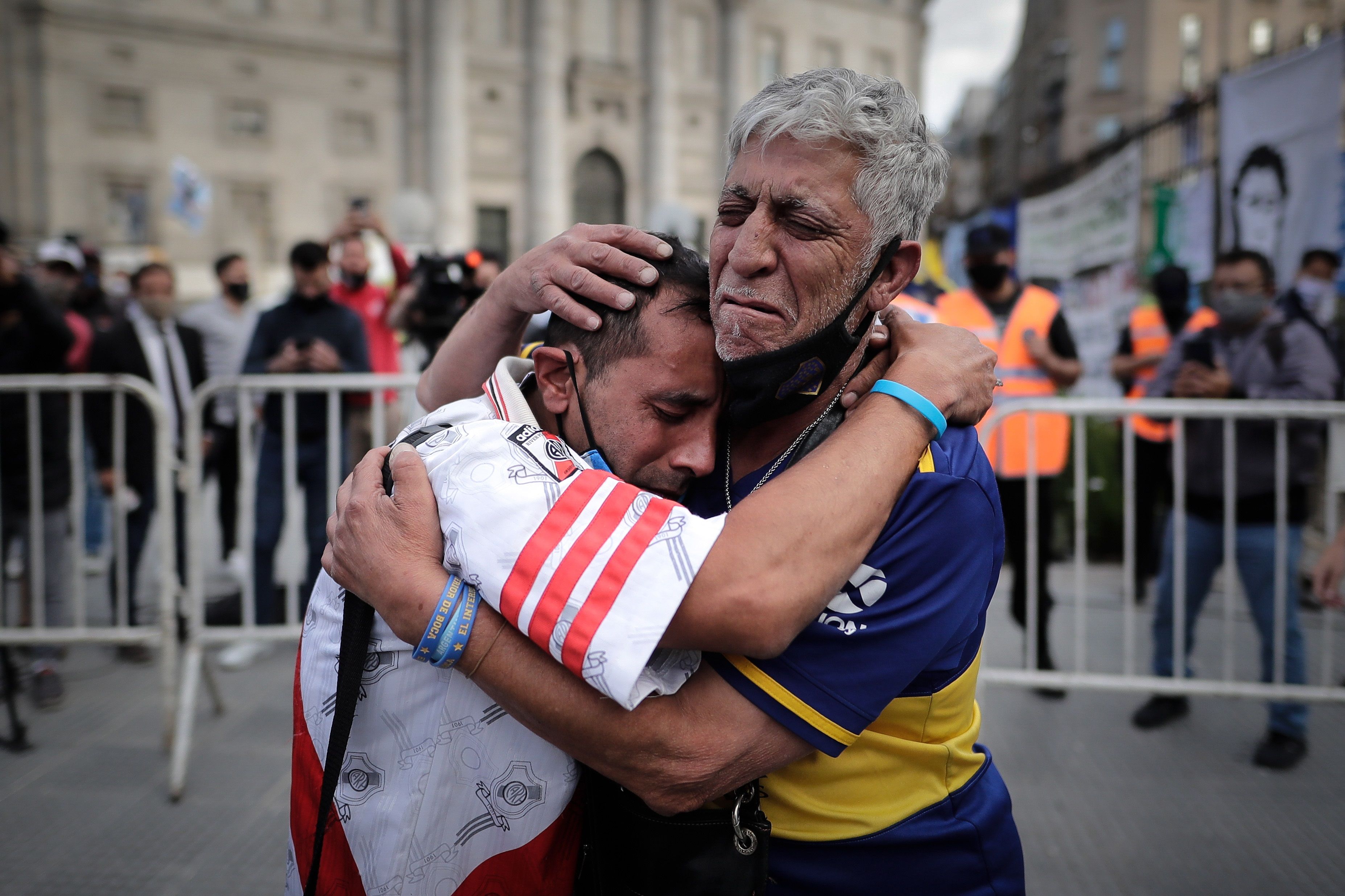 Un aficionado con la camiseta de Boca Juniors y otro con la de River Plate, se abrazan luego de despedir los restos de Diego Armando Maradona en el velatorio de la capital bonaerense, en la Plaza de Mayo. Foto Prensa Libre: EFE.