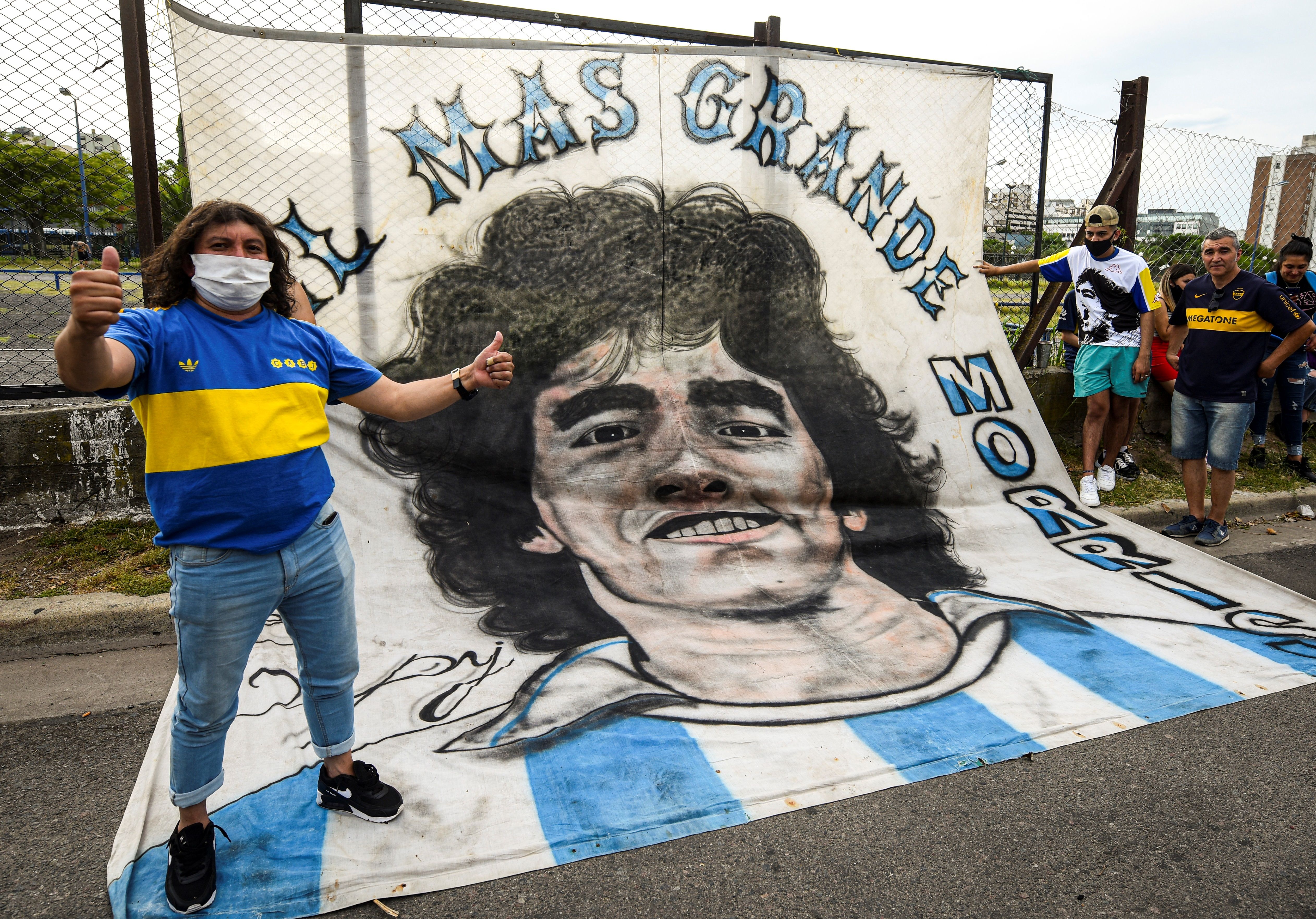 JJPANA7704. BUENOS AIRES (ARGENTINA), 29/11/2020.- Un aficionado posa junto a una pancarta con la imagen de Diego Armando Maradona hoy, antes del partido de la Primera División argentina entre Boca Juniors y Newell's Old Boys en el estadio La Bombonera en Buenos Aires (Agentina). Tras la muerte de Maradona el torneo argentino pasó a llamarse Diego Mardona 2020. EFE/MARCELO ENDELLI POOL