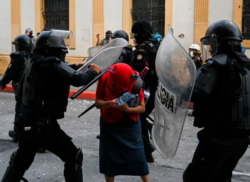 Policías golpean a una de las manifestantes que participó en las protestas contra el gobierno de Alejandro Giammattei y los diputados oficialistas que aprobaron el presupuesto nacional para 2021 (Foto Prensa Libre: AFP)