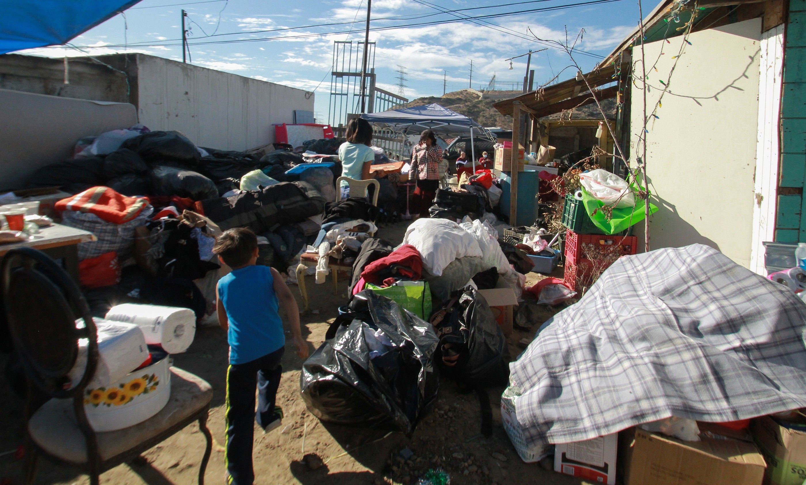 Migrantes centroamericanos que residen en un albergue en la ciudad mexicana de Tijuana, llevan apoyo en especie a familias que perdieron sus hogares. (Foto Prensa Libre: EFE)