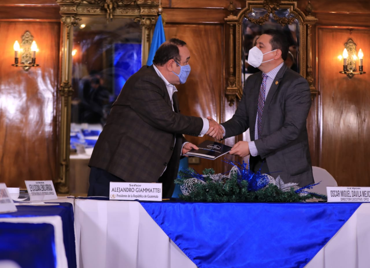 El presidente Alejandro Giammattei (Izq.) recibe el informe de manos de Óscar Dávila, director ejecutivo de la Comisión contra la Corrupción. (Foto: Gobierno de Guatemala)