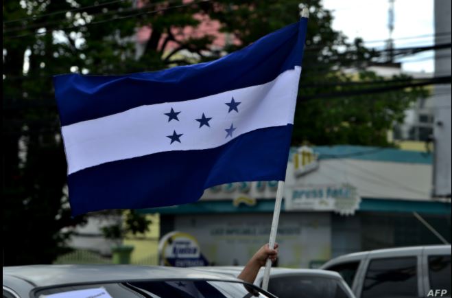 Un hombre sostiene la bandera nacional de Honduras mientras participa en una caravana por el Boulevard Morazán, el 15 de julio de 2020. (Foto Prensa Libre: AFP)