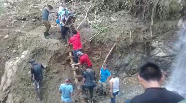 Personas ayudan a trasladar aun adulto mayor ante la falta de carreteras que comunican a la aldea Palo Grande, en Chiantla. (Foto Prensa Libre)