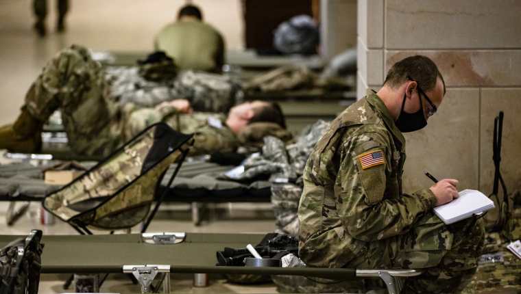 Soldados de la Guardia Nacional estadounidense toman un descanso en el centro de visitantes del Capitolio, en Washington. (Foto Prensa Libre: AFP)