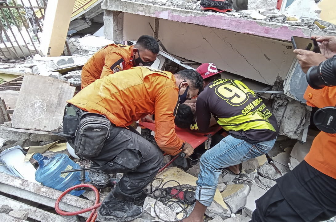 En Mamuju, Indonesia, los socorristas sacan a uno sobreviviente de un edificio colapsado por el terremoto de 6.2 que azotó el país. (Foto Prensa Libre: EFE)