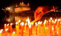 A Sikh devotee lights candles on the occasion of the birth anniversary of the 10th Sikh Guru Gobind Singh, at the illuminated Golden Temple in Amritsar on January 20, 2021. (Photo by NARINDER NANU / AFP)