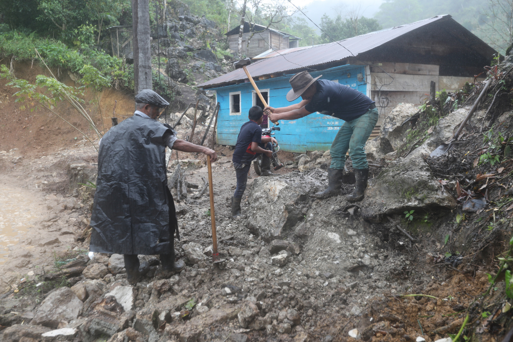 Roberto Choc pica la piedra para removerla de su casa, dañada por la inundación que cubrió dos meses la aldea. Foto: Érick Ávila