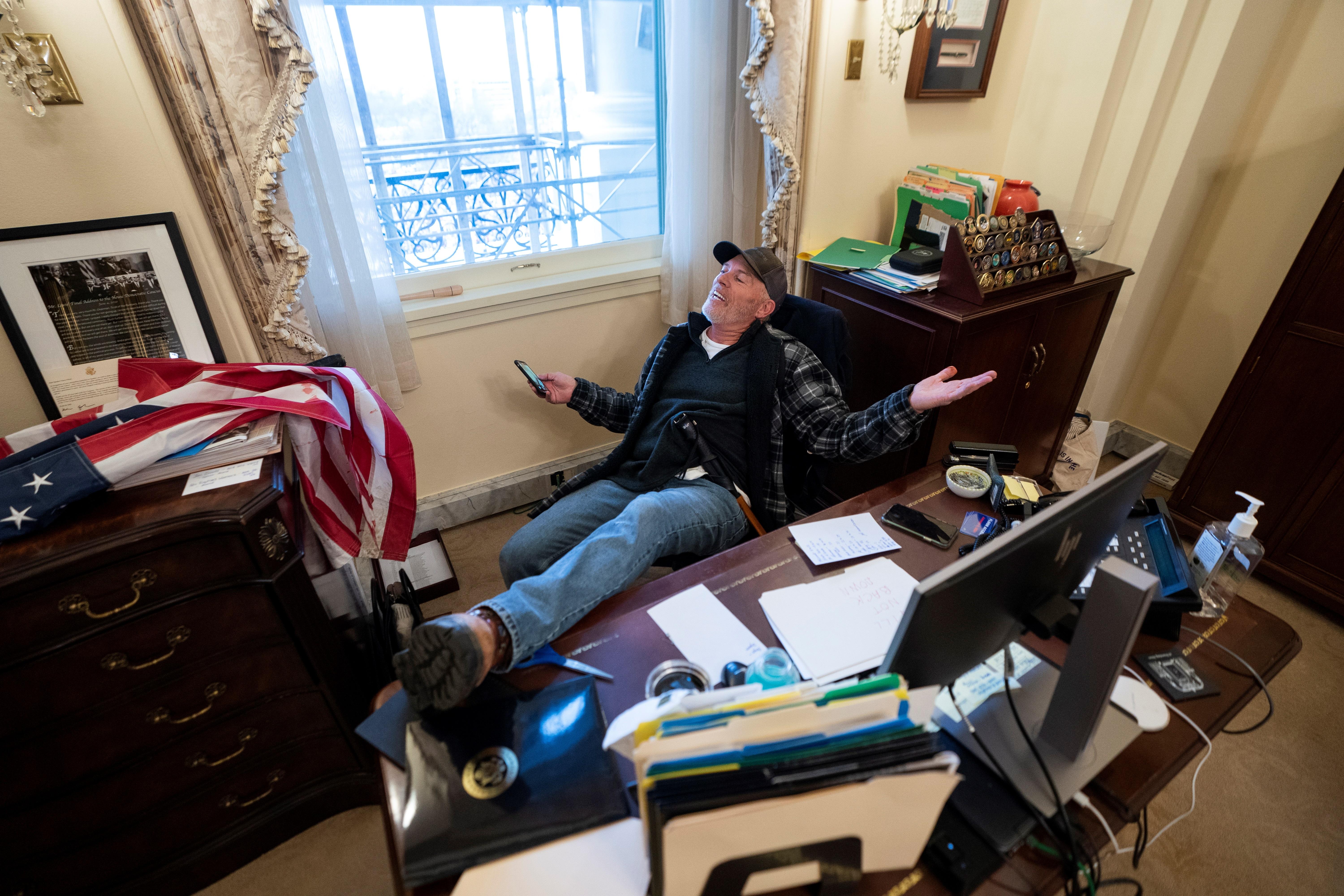 Un seguidor de Donald Trump se sienta en el escritorio de la portavoz de la Cámara de Representantes de Estados Unidos, Nancy Pelosi, luego de irrumpir en el Capitolio estadounidense durante unas protestas en Washington. (Foto Prensa Libre: EFE)