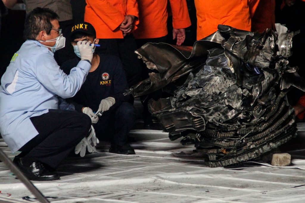 Autoridades inspeccionan las partes localizadas del avión de Sriwijaya Air, el cual se estrelló en Yakarta. (Foto Prensa Libre: AFP)