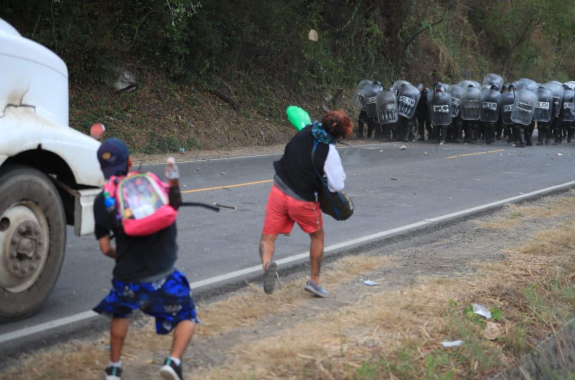 Migrantes lanzan piedras y botellas al contingente de la Policía que los desaloja en km 177 de Vado Hondo, Chiquimula, (Foto Prensa Libre: Carlos Hernández)