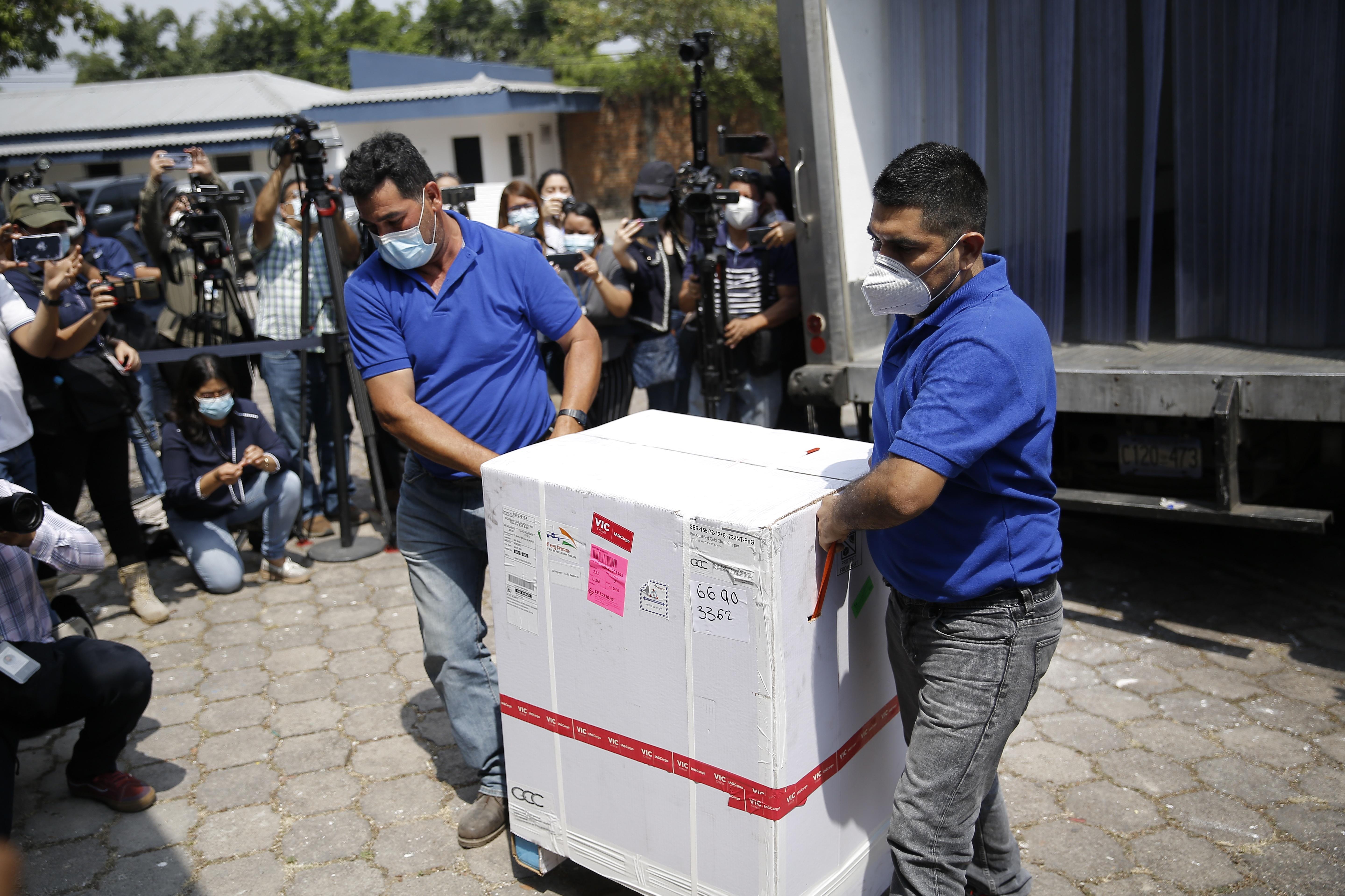 Dos hombres bajan de un camión una caja que contiene dosis de las vacunas contra la covid-19, en el Centro Nacional de Biológicos en Soyapango, El Salvador.  (Foto Prensa Libre: EFE)