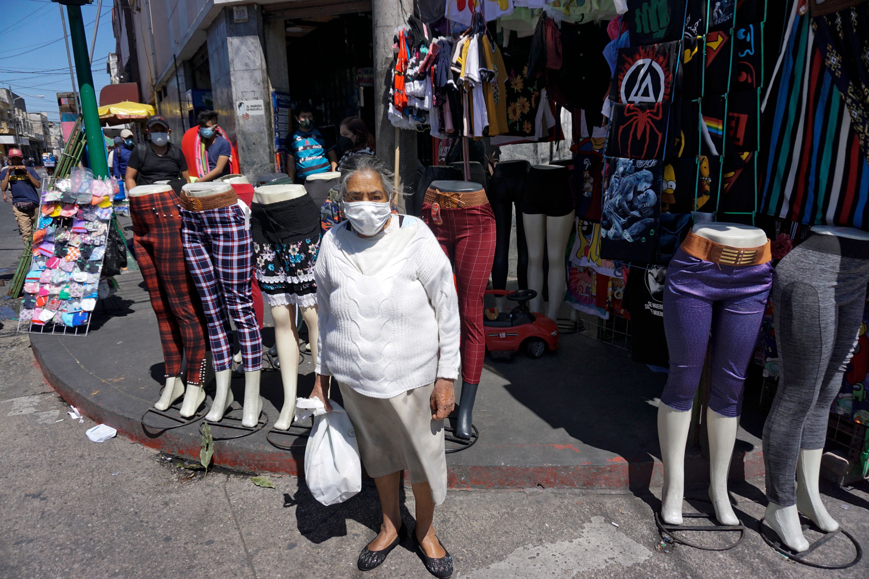 Una mujer mayor se protege con mascarillas en una calle de la capital, mientras se reporta otro descenso en los casos de coronavirus. (Foto Prensa Libre: AFP)