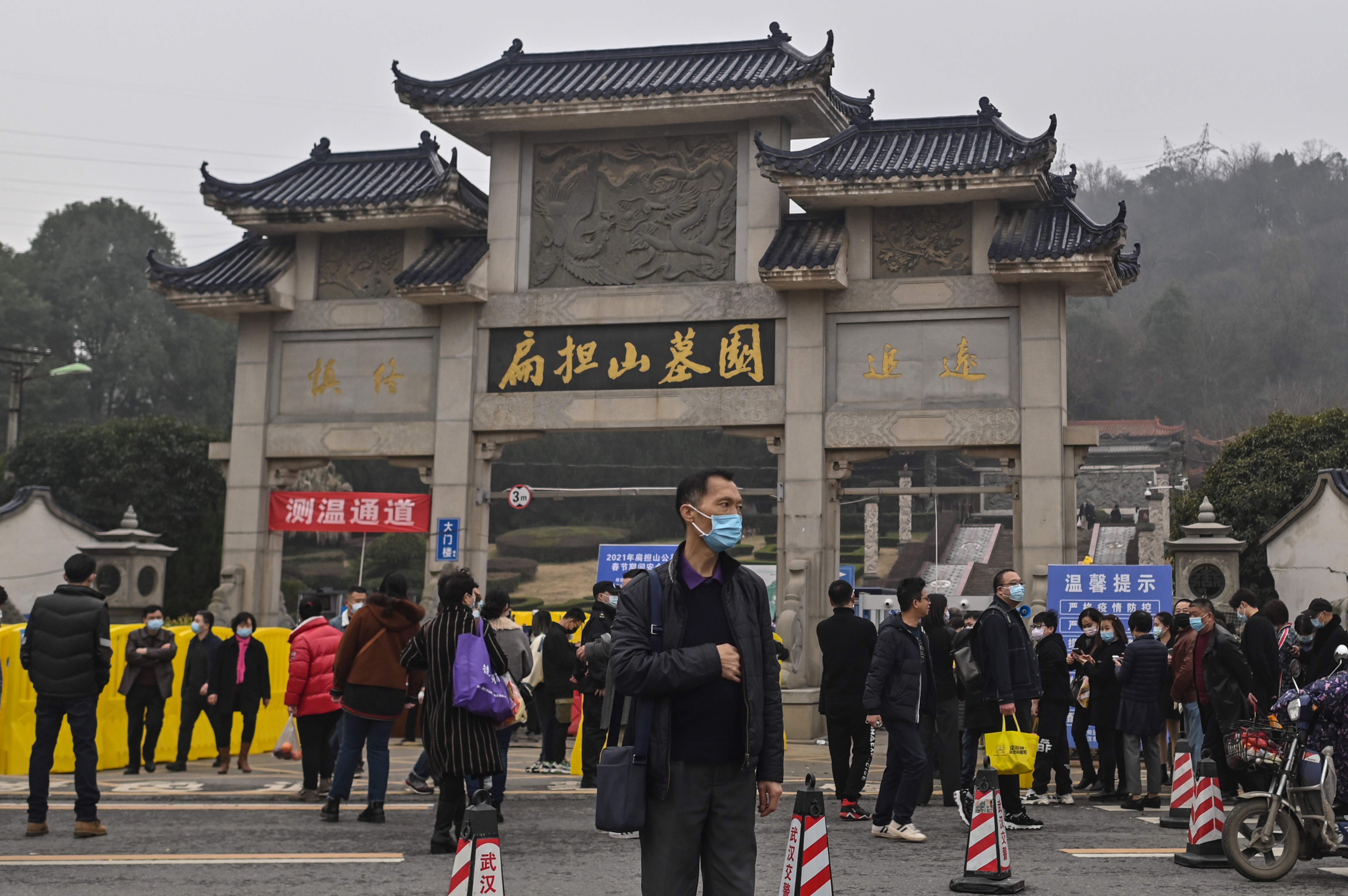 People are seen outside the Biandanshan cemetery in Wuhan, in China's central Hubei province on February 12, 2021, during the first day of the Lunar New Year, which ushers in the Year of the Ox. (Photo by Hector RETAMAL / AFP)
