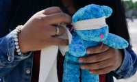 A demostrator holds a teddy bear with its eyes covered during a protest to demand justice for the murder of girls at Constitution Square in Guatemala City, on February 14, 2021. - The demonstrators, mostly girls and adolescents, also demand the strengthen of the safety politics to stop the upturn of violent acts in 2021, between them the murder of eight-year-old Sharon Figueroa, crime that generated an indignation wave. (Photo by Johan ORDONEZ / AFP)