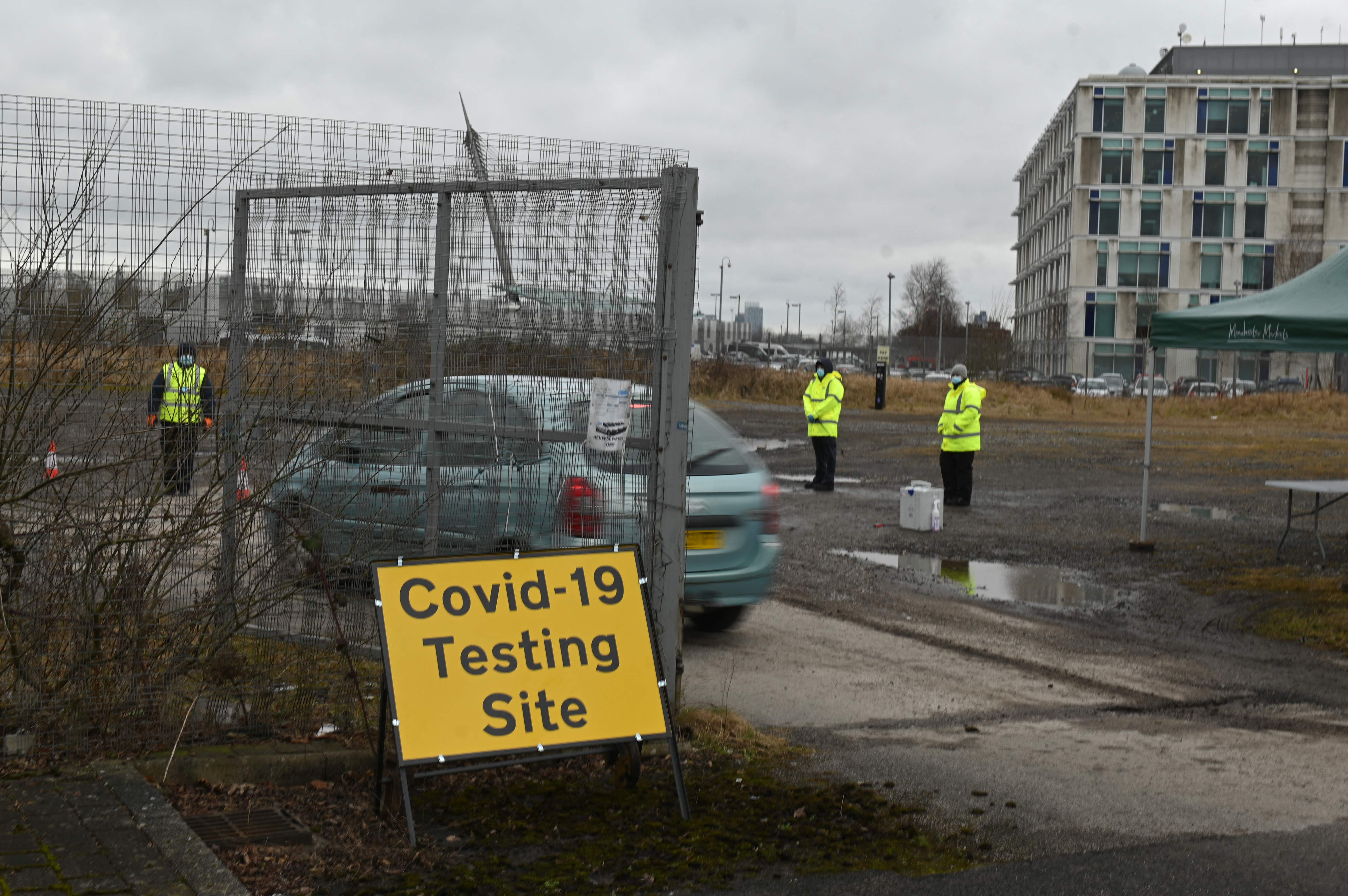 Un vehículo entra en una instalación temporal de pruebas de covid-19 en Moston, cerca de Manchester, el 19 de febrero de 2021, cuando un puñado de casos de una "variante preocupante" de covid-19 ha aparecido en la zona. (Foto Prensa Libre: AFP)