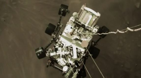 El robot Perseverance cuando estaba aterrizando en Marte, visto desde el cohete que ayudó en su descenso. NASA