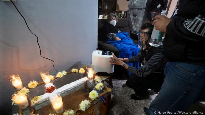 Entrega de un concentrador de oxígeno a una mujer con COVID-19, frente al altar de su marido, quien murió a causa del virus en Iztapalapa, México.	(Marco Ugarte/AP/picture alliance)
