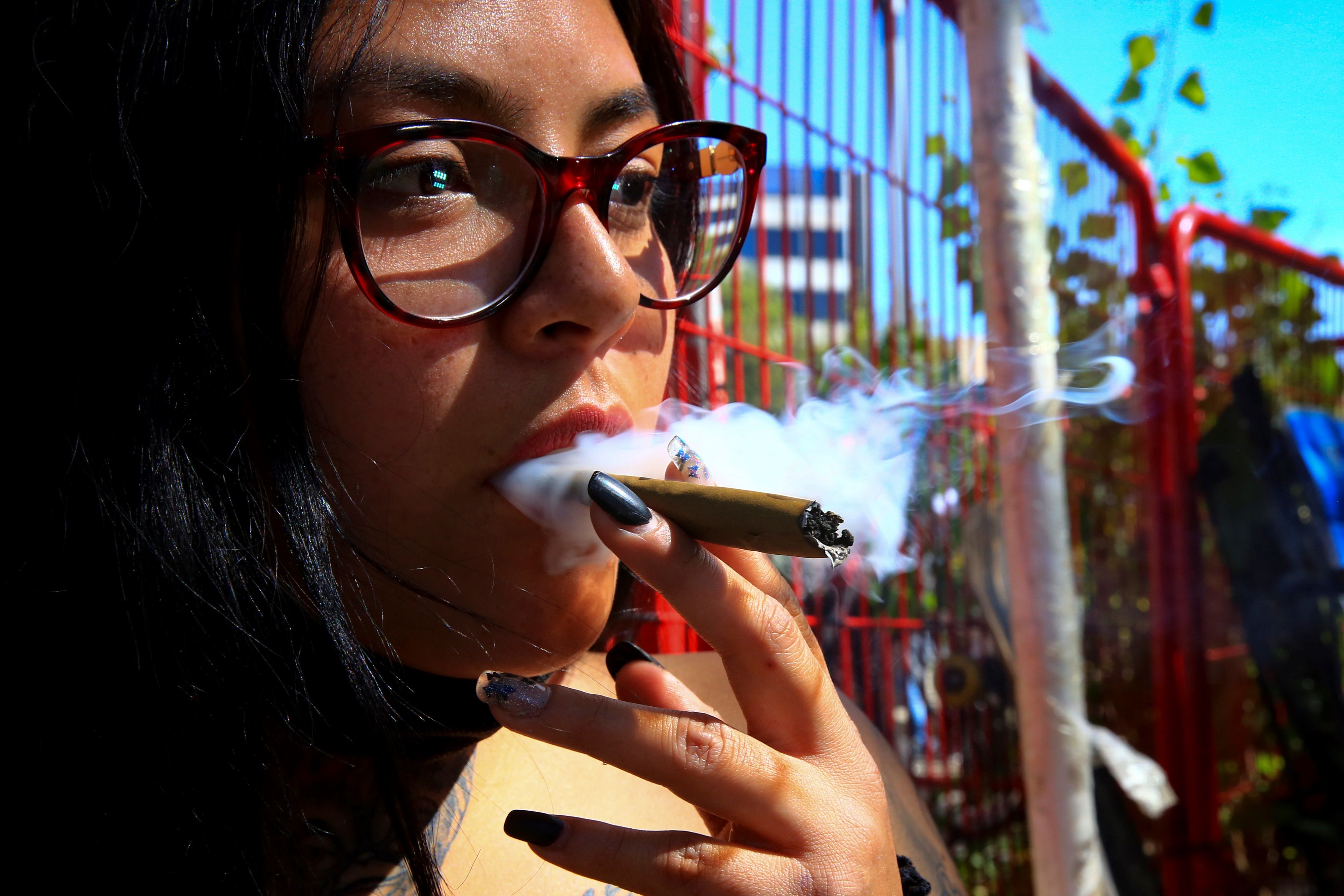 Una mujer fuma un cigarro de marihuana en el Zócalo de la Ciudad de México, donde la Cámara de Diputados aprobó la legislación que regula el consumo, el cultivo y el comercio de marihuana con fines recreativos en todo el territorio. (Foto Prensa Libre: EFE)