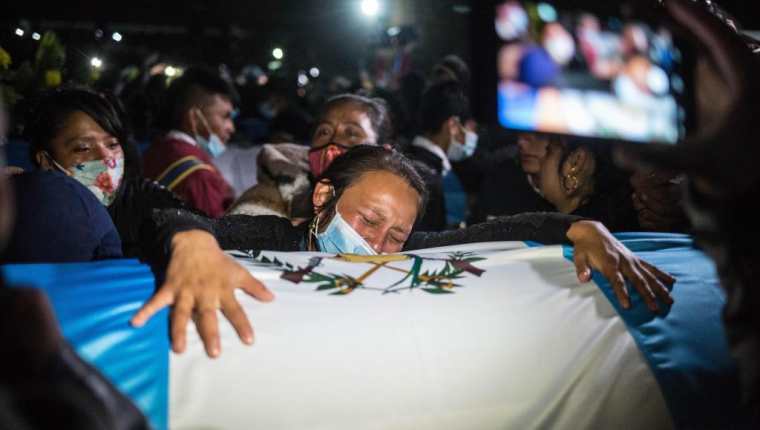 Sobre los ataúdes se colocaron banderas de Guatemala, además que familias portaron fotografías de las víctimas del asesinato.  (Foto Prensa Libre: EFE)