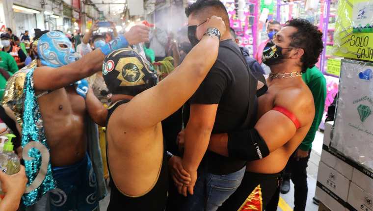 Los luchadores profesionales levantan a quienes no lleven mascarilla y los rocían con desinfectante. (Foto Prensa Libre: @CdeAbastoCDMX)