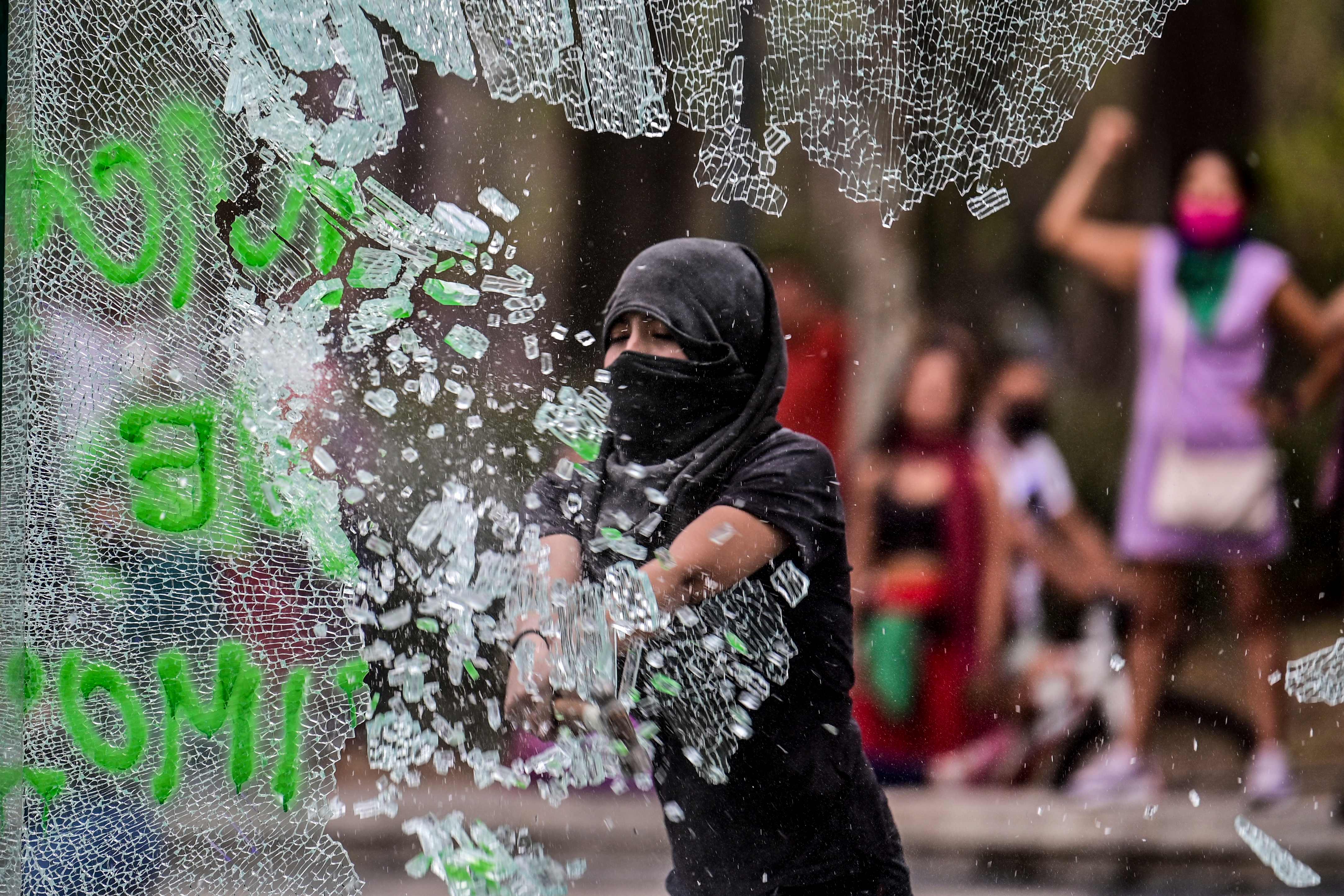 Una mujer destroza un vidrio en una estación del metro durante una marcha para conmemorar el Día Internacional de la Mujer en Ciudad de México. (Foto Prensa Libre: AFP)