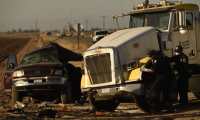 Investigators look over the scene of a crash between an SUV and a semi-truck full of gravel near Holtville, California on March 2, 2021. - At least 13 people were killed in southern California on Tuesday when a vehicle packed with passengers including minors collided with a large truck close to the Mexico border, officials said. (Photo by Patrick T. FALLON / AFP)