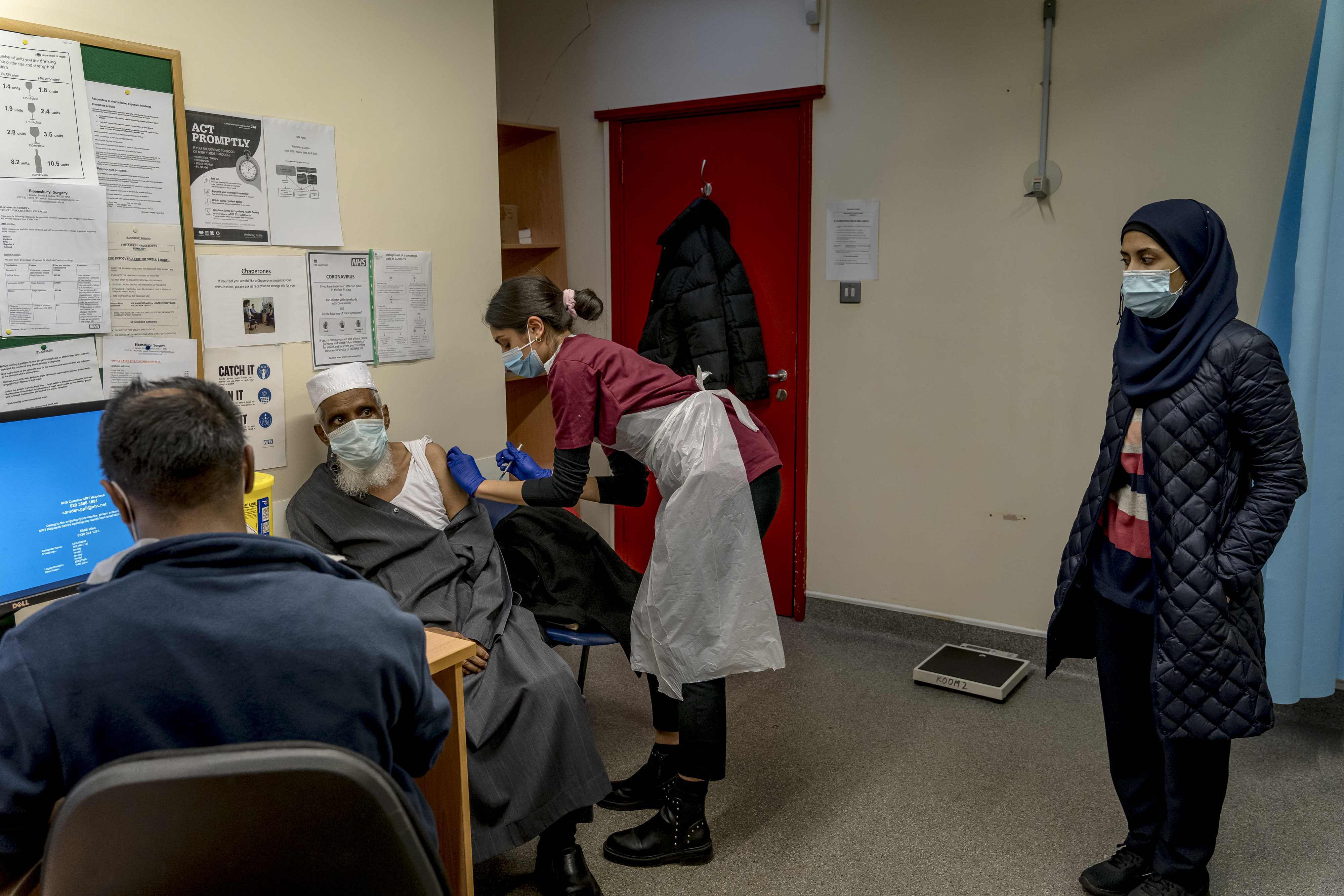 Una hija observa cómo su padre de 79 años se vacuna en Londres, el 28 de enero de 2021.(Andrew Testa/The New York Times)