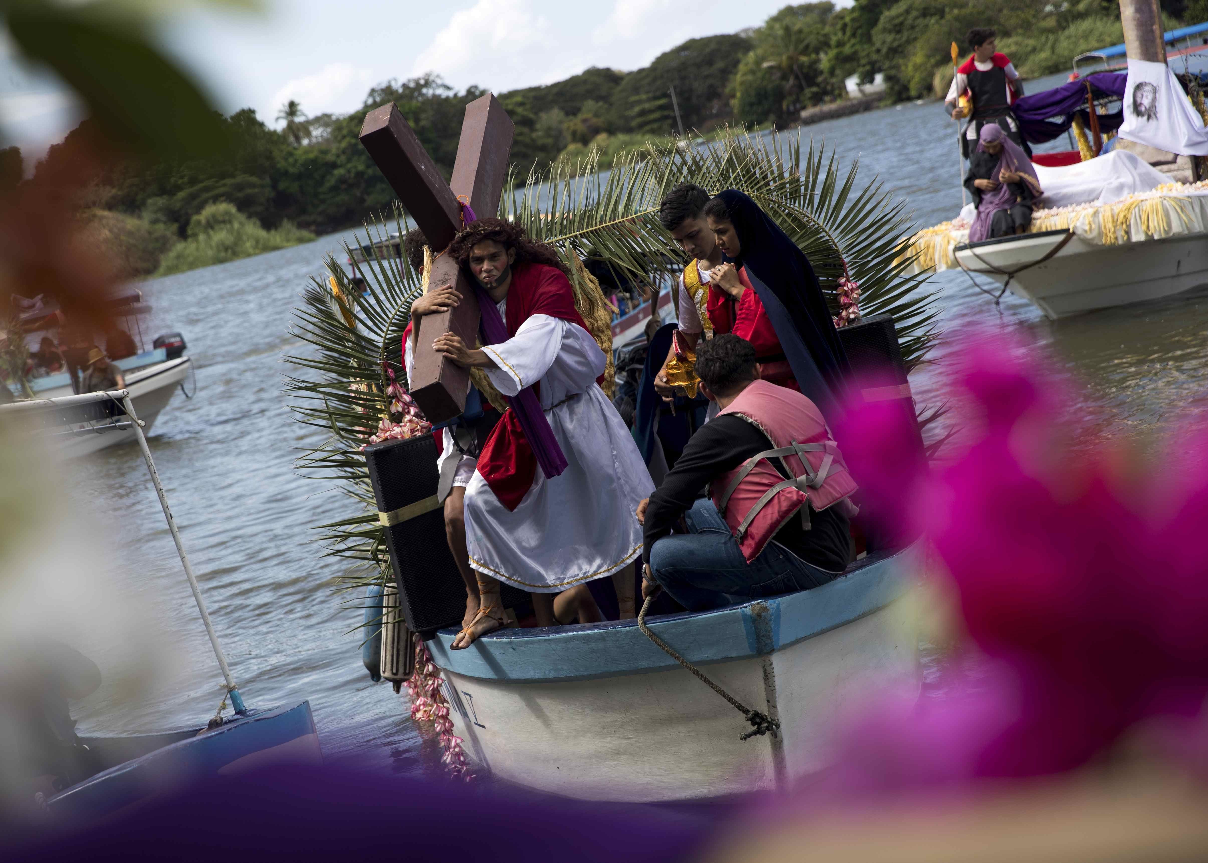 Un hombre carga una cruz en una embarcación durante el viacrucis acuático, en Granada, Nicaragua. (Foto Prensa Libre: EFE)