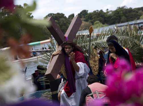 Un hombre carga una cruz en una embarcación durante el viacrucis acuático, en Granada, Nicaragua. (Foto Prensa Libre: EFE)