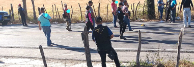 Policías, fiscales y hombres vestidos de civil con armamento pesado rodean la escena donde se observa, además, casquillos en el asfalto.