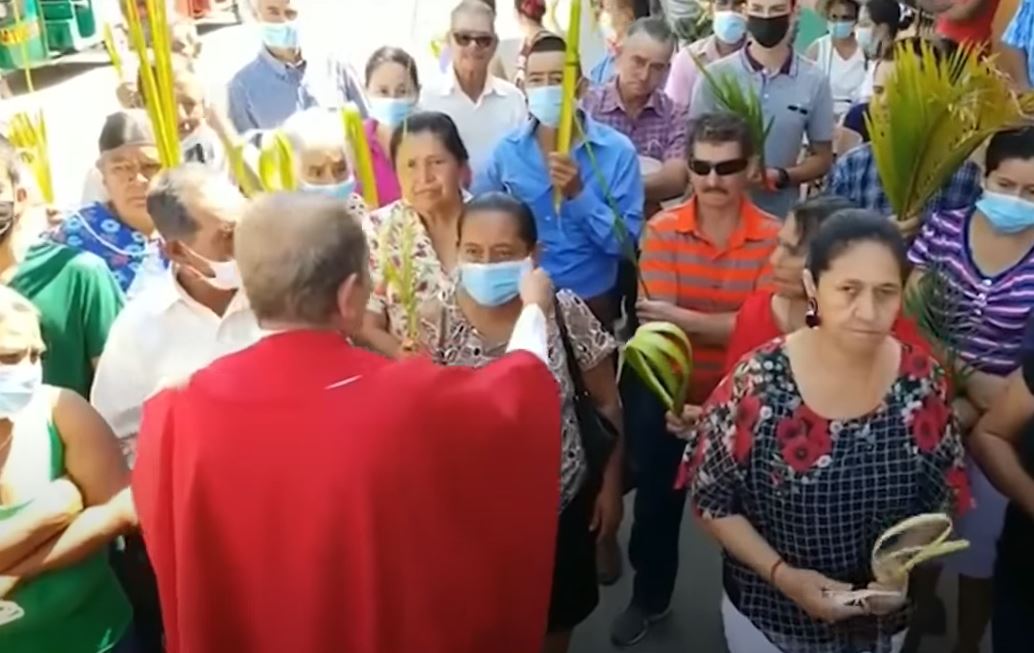 El sacerdote Rolando Peña le arrebata la mascarilla a una mujer  durante las actividades de Domingo de Ramos en Corquín, Copán, Honduras. (Foto Prensa Libre: Captura de video)