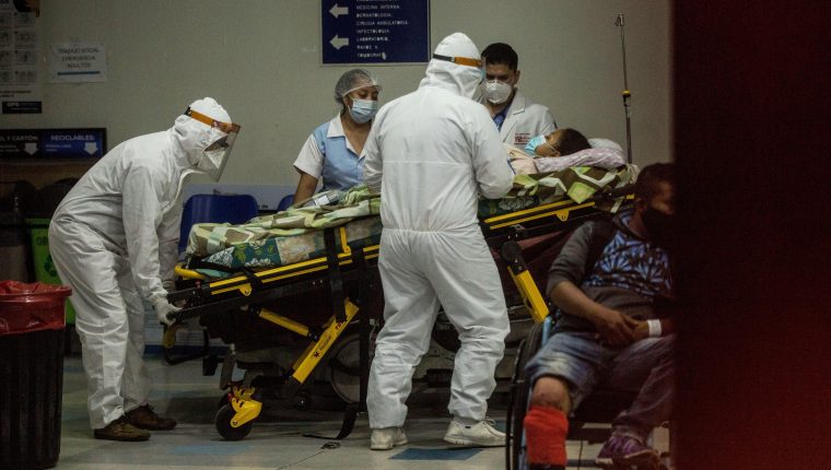Paramédicos con equipo de protección para evitar el contagio de coronavirus ingresan a una mujer al área de emergencias del Hospital San Juan de Dios. (Foto Prensa Libre: EFE)