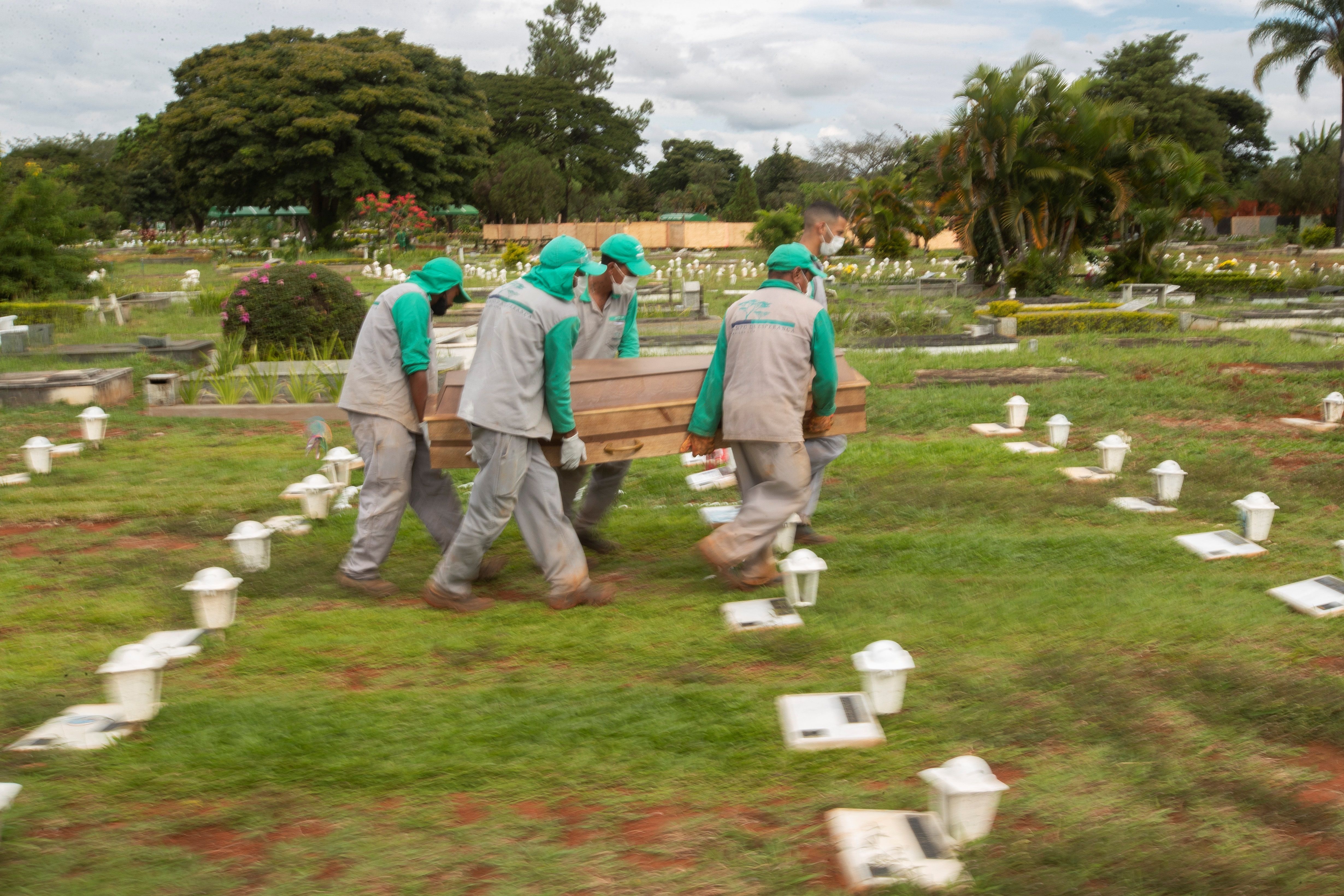 Trabajadores cargan el féretro para enterrar a una víctima de covid-19  en el cementerio Campo da Esperança, en la ciudad de Brasilia. Foto Prensa Libre: EFE. 