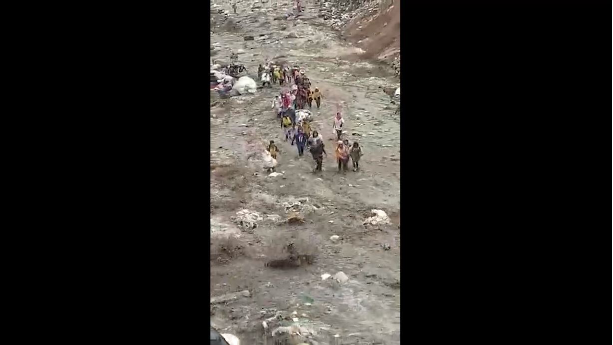 Un grupo de guajeros avanza entre la correntada de lodo, agua y desechos en el vertedero de la zona 3. (Foto Prensa Libre: Captura de pantalla)