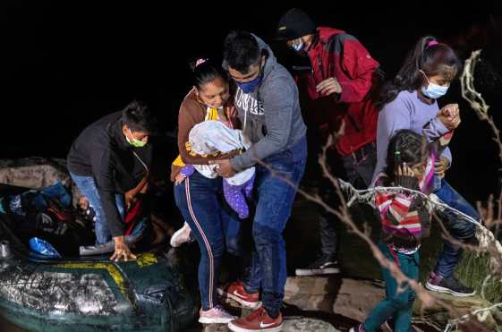 Los padres controlan a su bebé en la orilla del Río Grande después de que fueron contrabandeados a través de la frontera entre Estados Unidos y México en Roma, Texas. (Foto Prensa Libre: AFP)