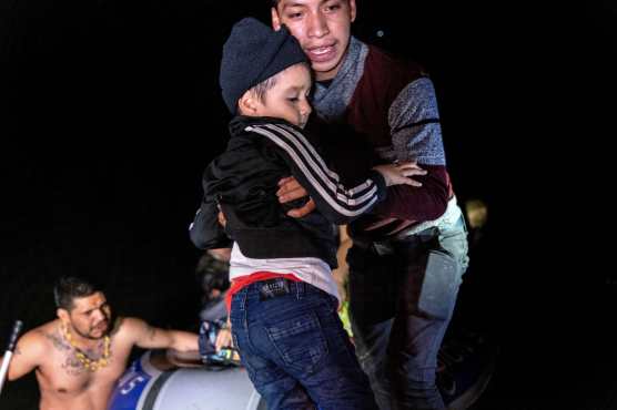 Un migrante adolescente lleva a un niño más joven a suelo estadounidense después de que un traficante de personas los sacara de contrabando a través de la frontera entre Estados Unidos y México en Roma, Texas. (Foto Prensa Libre: AFP)